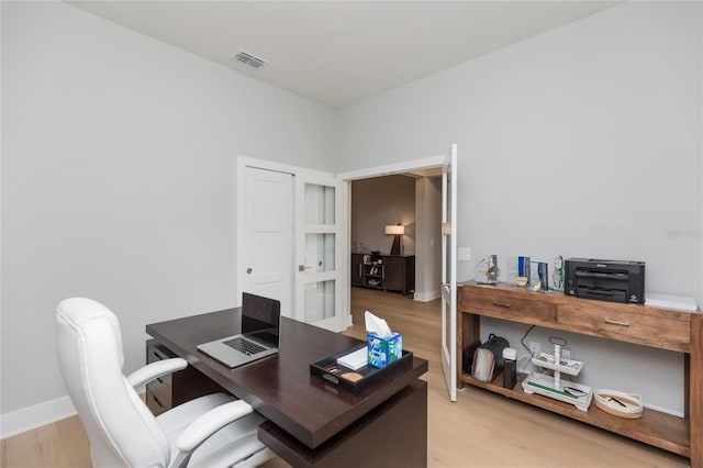 home office featuring visible vents, light wood finished floors, and baseboards