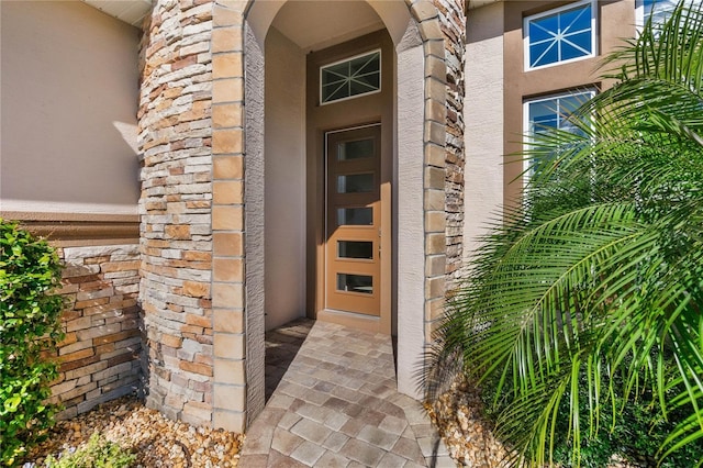 doorway to property featuring stone siding and stucco siding