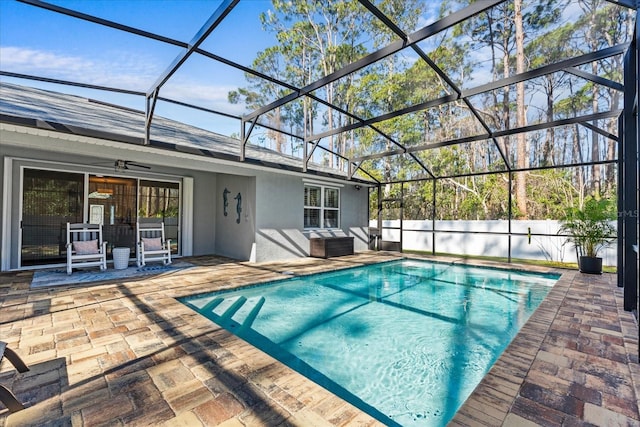 view of pool featuring a patio, an outdoor hangout area, ceiling fan, and glass enclosure