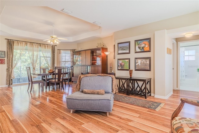 sitting room featuring a tray ceiling, light hardwood / wood-style floors, and ceiling fan