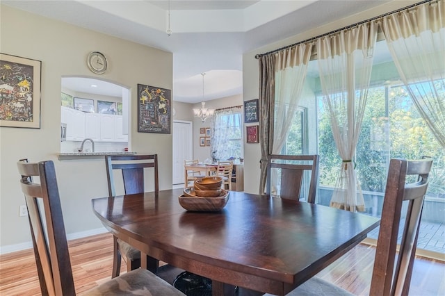 dining space with a chandelier, sink, and light wood-type flooring