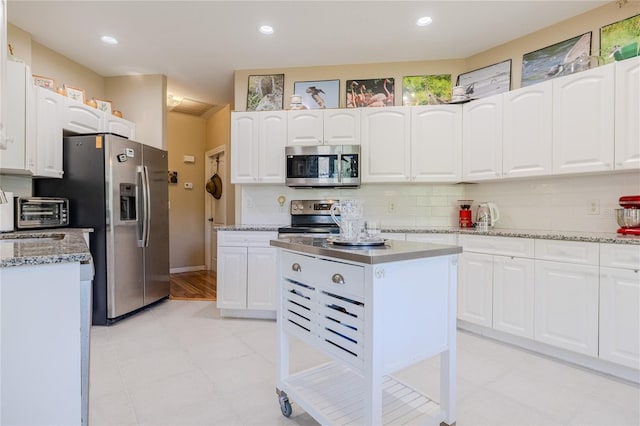 kitchen featuring white cabinetry, decorative backsplash, stainless steel appliances, and a kitchen island