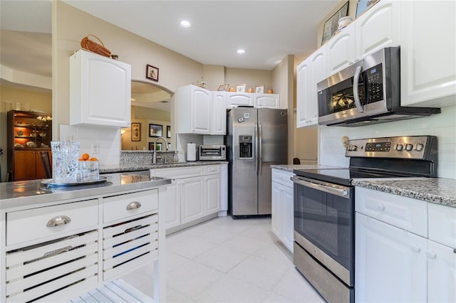 kitchen with tasteful backsplash, appliances with stainless steel finishes, sink, and white cabinets