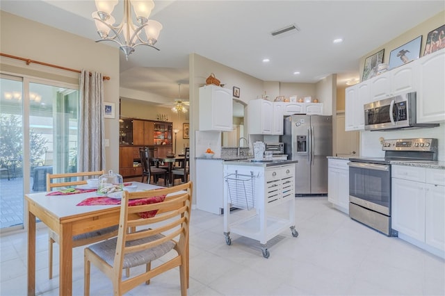 kitchen featuring stainless steel appliances, decorative light fixtures, dark stone counters, and white cabinets