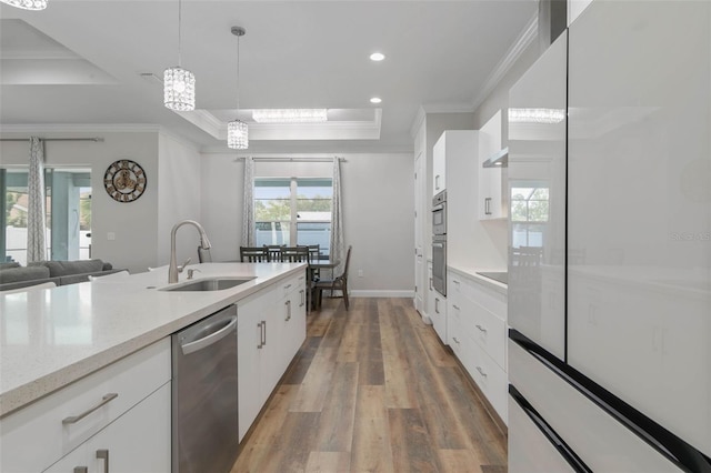 kitchen featuring appliances with stainless steel finishes, a tray ceiling, sink, and white cabinets