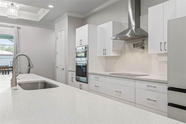 kitchen with double oven, white cabinetry, sink, black electric cooktop, and wall chimney exhaust hood