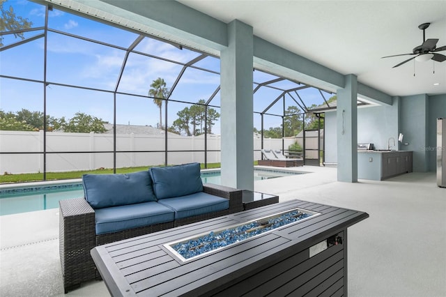 view of patio featuring an outdoor kitchen, sink, a lanai, ceiling fan, and an outdoor living space with a fire pit