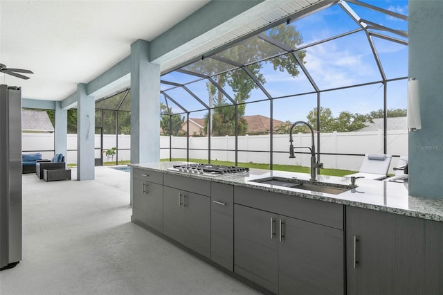 view of patio with area for grilling, a lanai, and sink