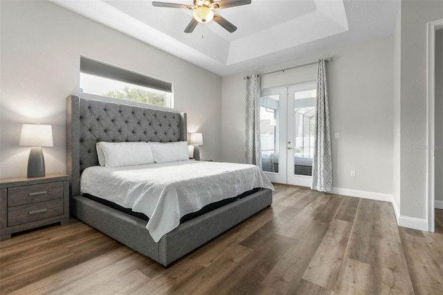 bedroom with a raised ceiling, wood-type flooring, access to exterior, and french doors