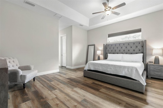 bedroom featuring a tray ceiling, dark hardwood / wood-style floors, and ceiling fan