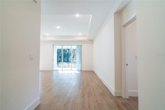 unfurnished room with a tray ceiling and light hardwood / wood-style floors