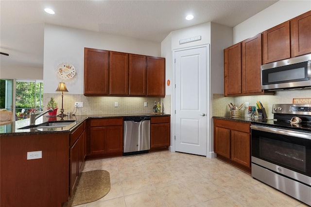 kitchen with appliances with stainless steel finishes, sink, backsplash, and dark stone counters