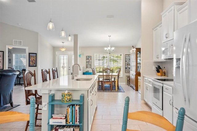 kitchen featuring an island with sink, sink, white cabinets, hanging light fixtures, and white appliances