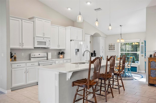 kitchen featuring white cabinetry, white appliances, decorative light fixtures, and a center island with sink