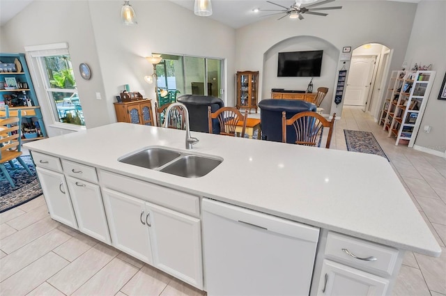 kitchen with sink, vaulted ceiling, white dishwasher, a kitchen island with sink, and white cabinets