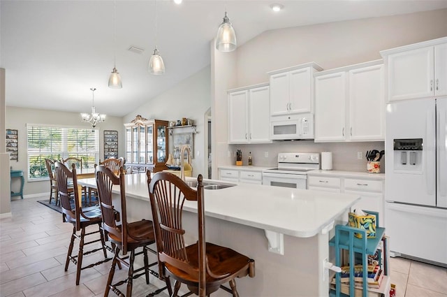 kitchen with white cabinets, a kitchen bar, a kitchen island with sink, and white appliances