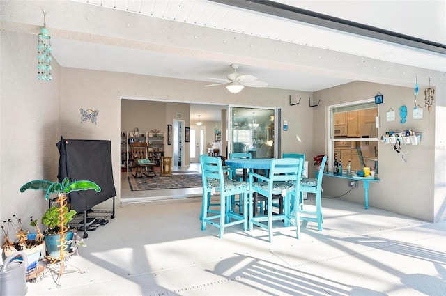 dining room featuring beamed ceiling, concrete flooring, and ceiling fan