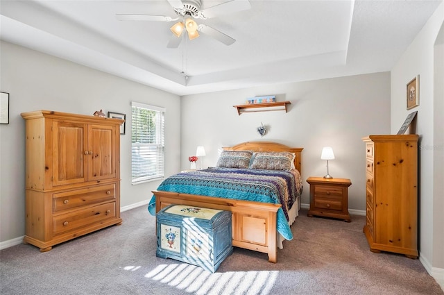 carpeted bedroom with a raised ceiling and ceiling fan