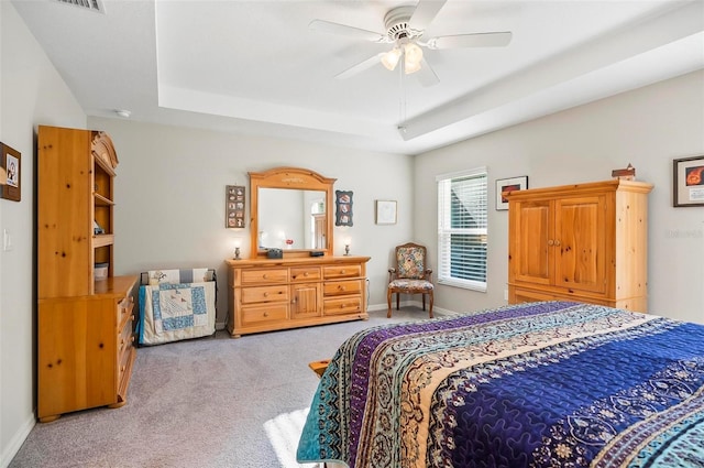 carpeted bedroom featuring a tray ceiling and ceiling fan