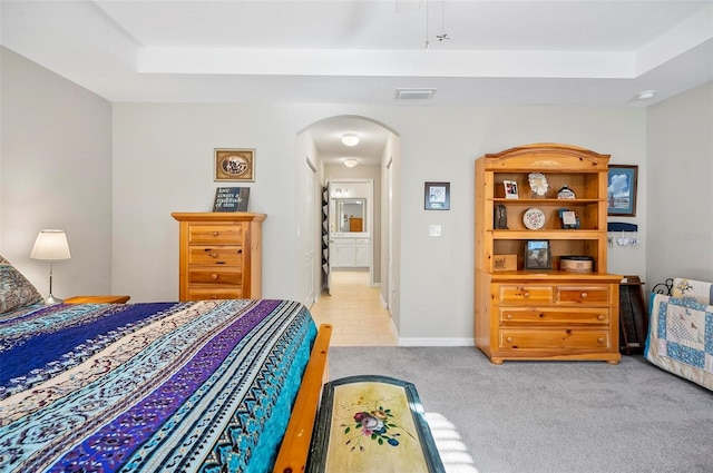 bedroom featuring light colored carpet and a raised ceiling