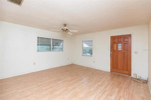 spare room with ceiling fan, light hardwood / wood-style flooring, and a textured ceiling
