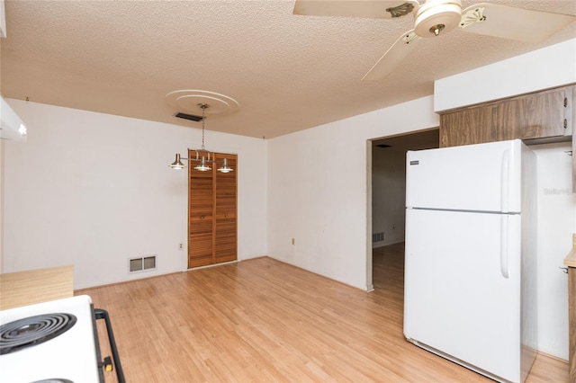 kitchen featuring range with electric stovetop, white fridge, ceiling fan, a textured ceiling, and light hardwood / wood-style flooring