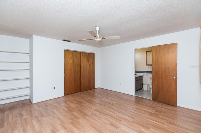 unfurnished bedroom with ensuite bathroom, ceiling fan, a textured ceiling, and light hardwood / wood-style flooring