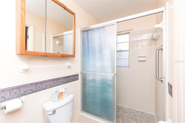bathroom featuring a shower with shower door and toilet