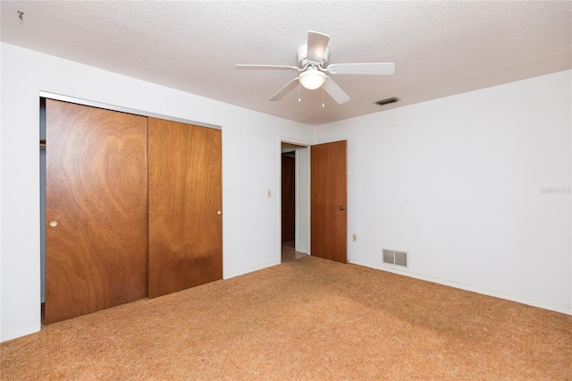 unfurnished bedroom featuring ceiling fan, a closet, a textured ceiling, and carpet