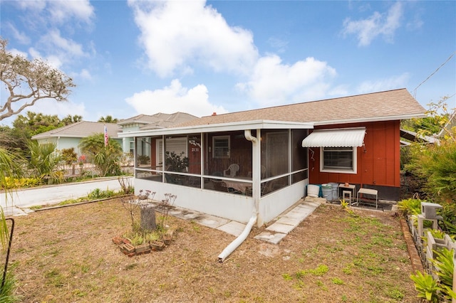 back of house featuring a sunroom and a lawn