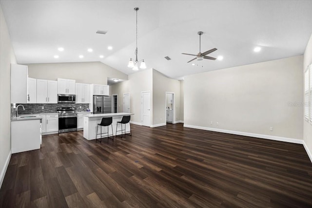 kitchen featuring a kitchen island, appliances with stainless steel finishes, a breakfast bar, white cabinetry, and hanging light fixtures