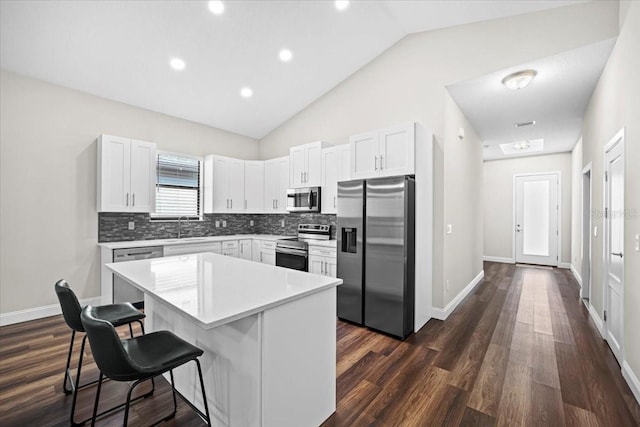 kitchen with appliances with stainless steel finishes, a center island, white cabinets, and a kitchen breakfast bar