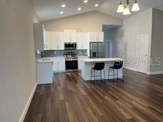 kitchen featuring pendant lighting, white cabinetry, decorative backsplash, a center island, and stainless steel appliances