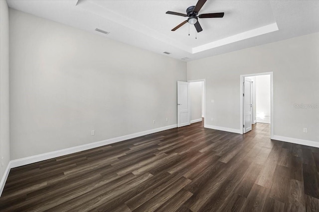 unfurnished room with dark wood-type flooring, ceiling fan, and a tray ceiling