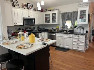 kitchen with appliances with stainless steel finishes, white cabinetry, sink, dark hardwood / wood-style flooring, and hanging light fixtures