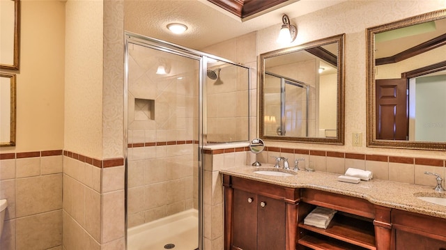 bathroom with a shower stall, tile walls, and a sink