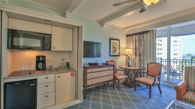 interior space featuring ceiling fan, ornamental molding, beamed ceiling, and indoor wet bar