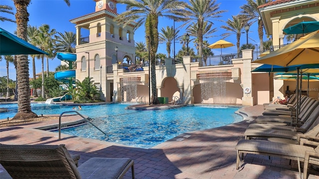 pool with a water slide, a patio area, and fence