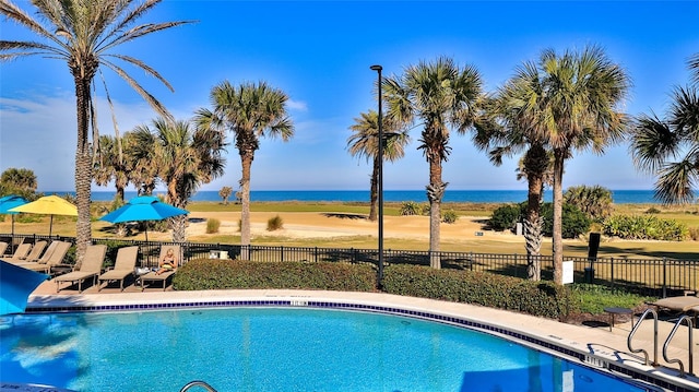 community pool with a water view and fence