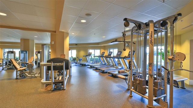 workout area with recessed lighting, plenty of natural light, a paneled ceiling, and baseboards