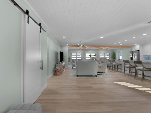 living room featuring ceiling fan, a barn door, wooden ceiling, and light hardwood / wood-style floors