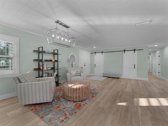 living area featuring a chandelier, light hardwood / wood-style flooring, ornamental molding, a barn door, and a baseboard heating unit