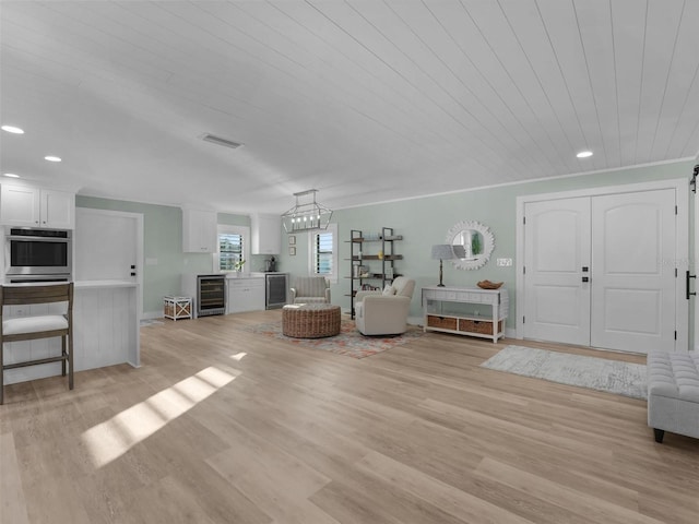 unfurnished living room with wine cooler, sink, wood ceiling, and light hardwood / wood-style flooring