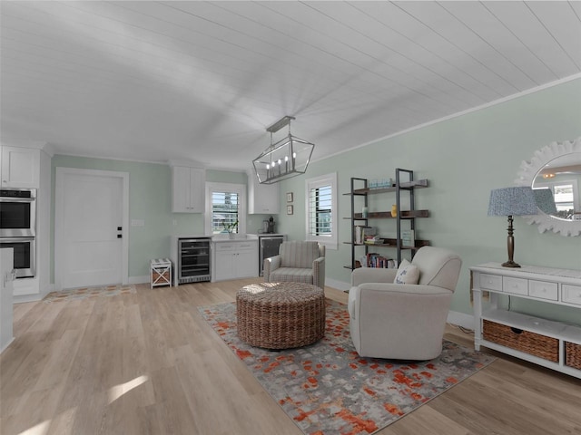 living room featuring ornamental molding, indoor bar, wine cooler, and light hardwood / wood-style flooring