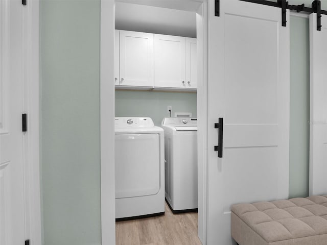 laundry area featuring independent washer and dryer, cabinets, and a barn door