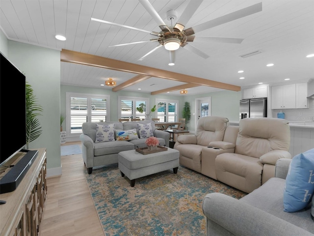 living room featuring ceiling fan, light hardwood / wood-style flooring, and beamed ceiling