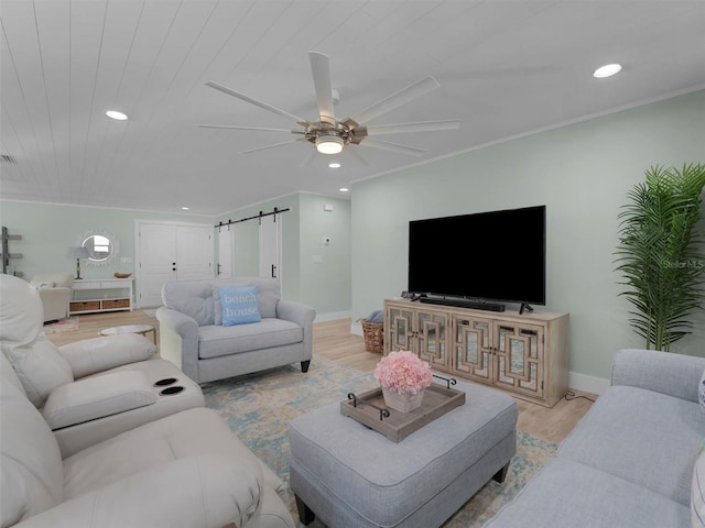 living room featuring crown molding, ceiling fan, a barn door, and light hardwood / wood-style flooring