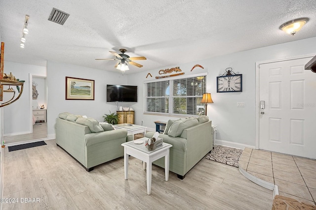 living room featuring ceiling fan, a textured ceiling, and light wood-type flooring