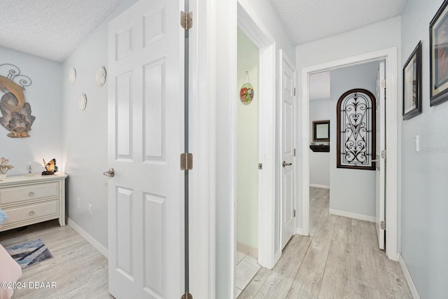 hall featuring a textured ceiling and light hardwood / wood-style flooring