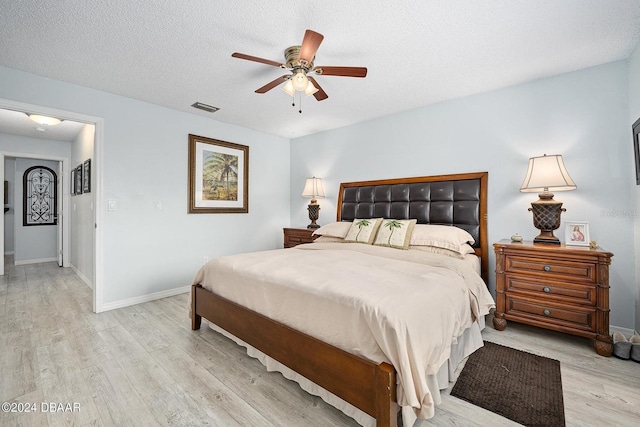 bedroom featuring ceiling fan, a textured ceiling, and light hardwood / wood-style floors